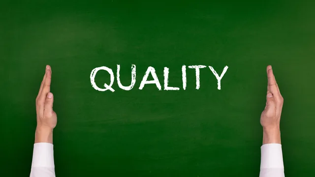 Hands framing the word Quality on a dark green chalkboard