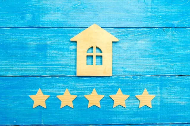 Wooden house shape above five wooden stars on a blue background