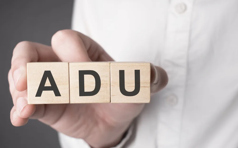 A hand holding wooden blocks spelling ADU