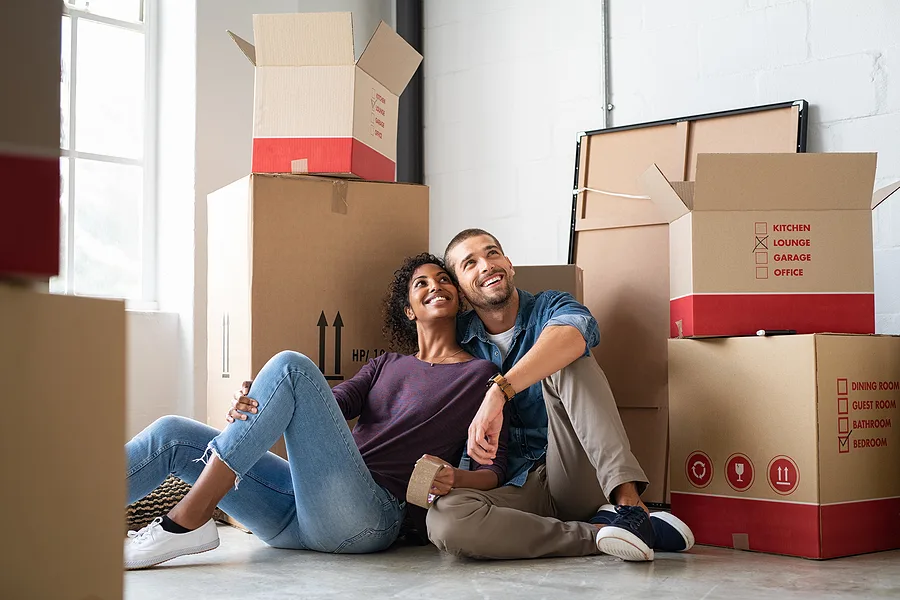 Couple sitting among packed moving boxes