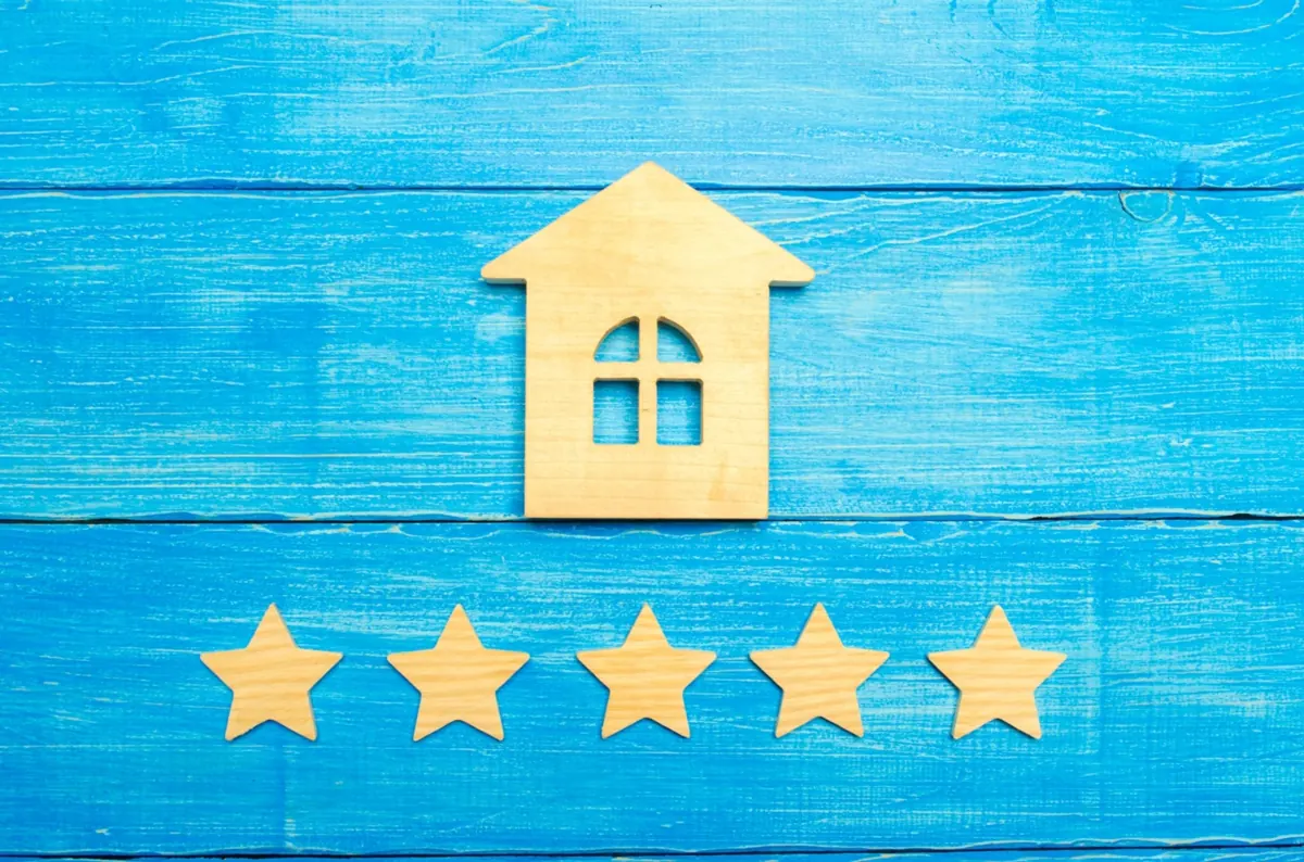 Wooden house shape above five wooden stars on a blue background