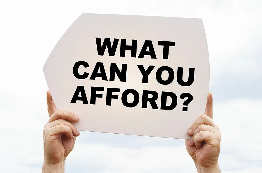 Person holding a sign asking what can you afford
