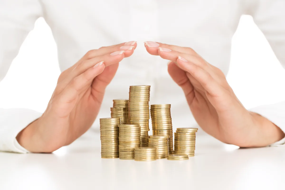 Hands protecting stacks of coins