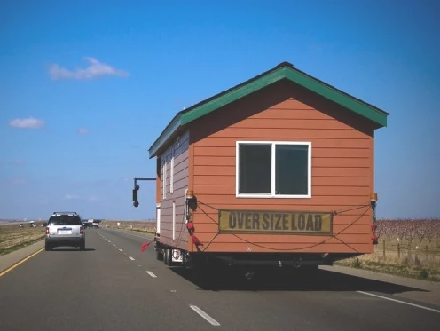 Tiny home being transported on a highway with an oversize load sign