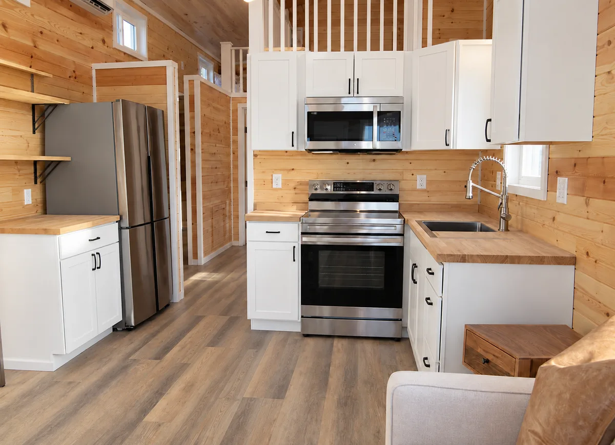 Tiny home kitchen with white cabinets and appliances