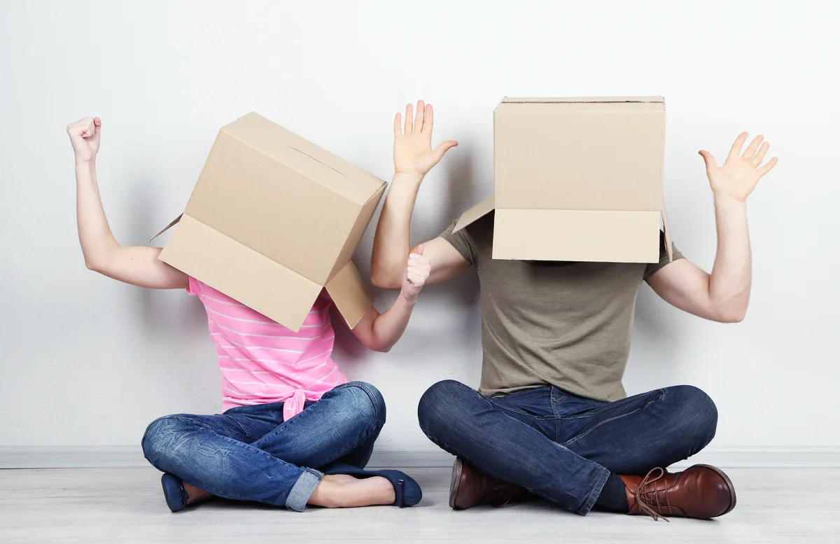 People holding moving boxes over their heads