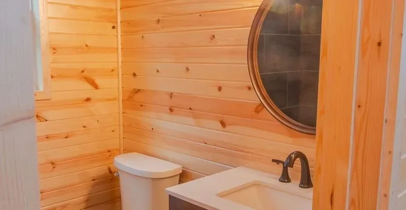 A tiny home bathroom with a round window and tub