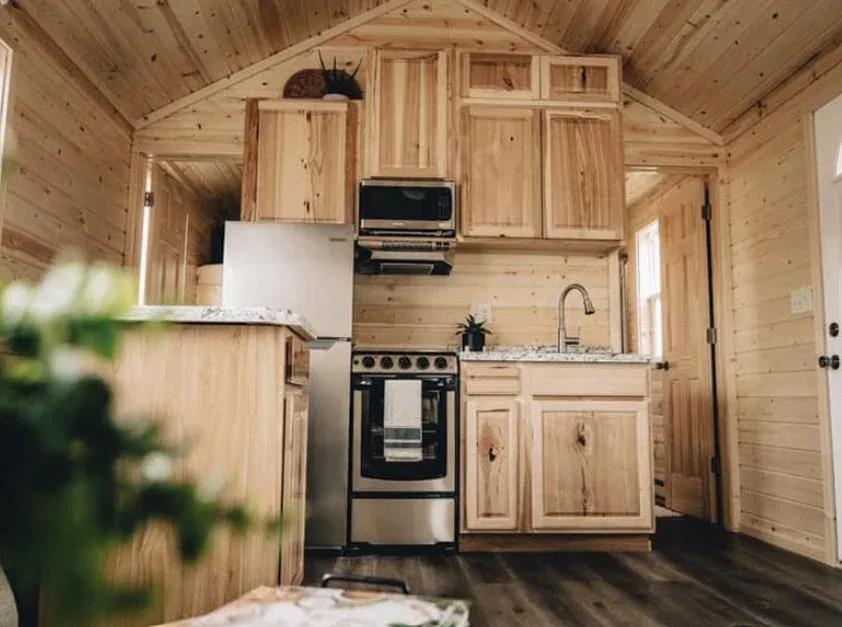 A compact tiny home kitchen with a range and cabinetry