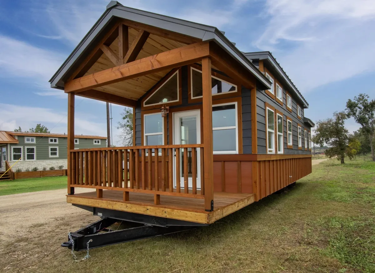 A wood park model tiny home with a large porch