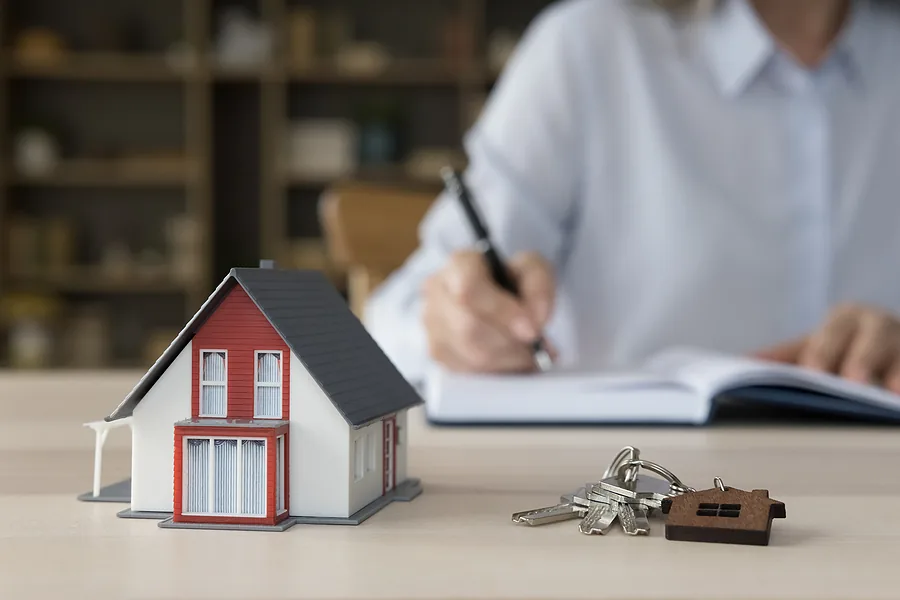 A model home, keys and a contract representing tiny home pricing