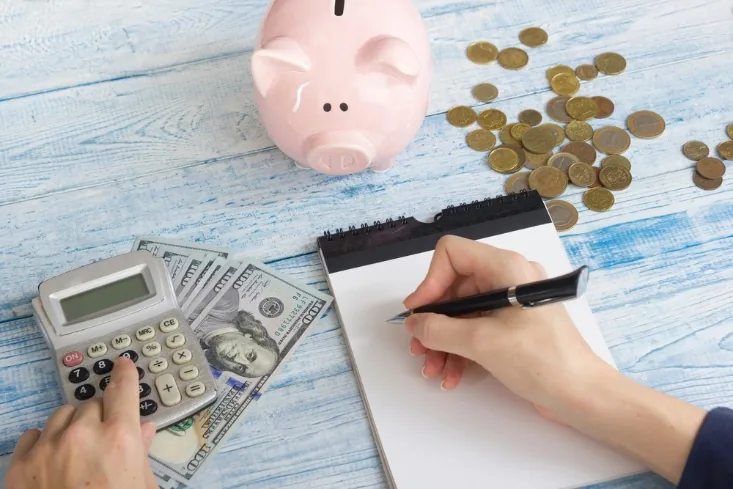 A calculator, cash and a piggy bank representing tiny home financing