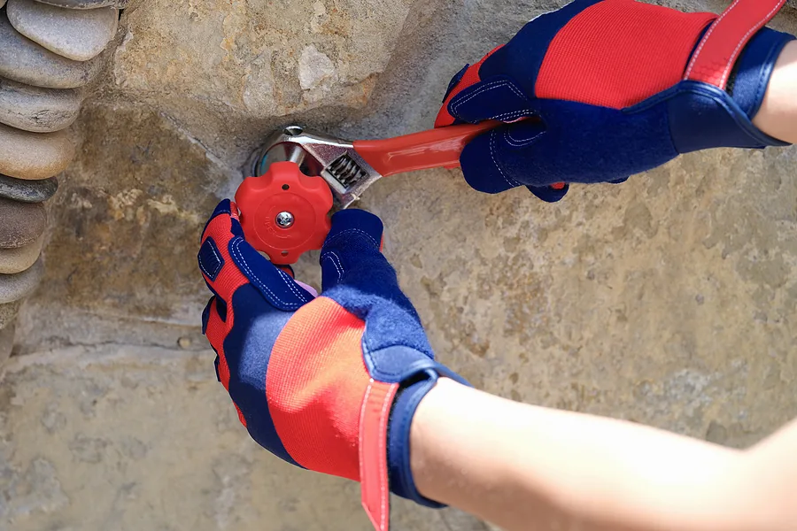 Hands connecting a tiny home's water and utility lines on site