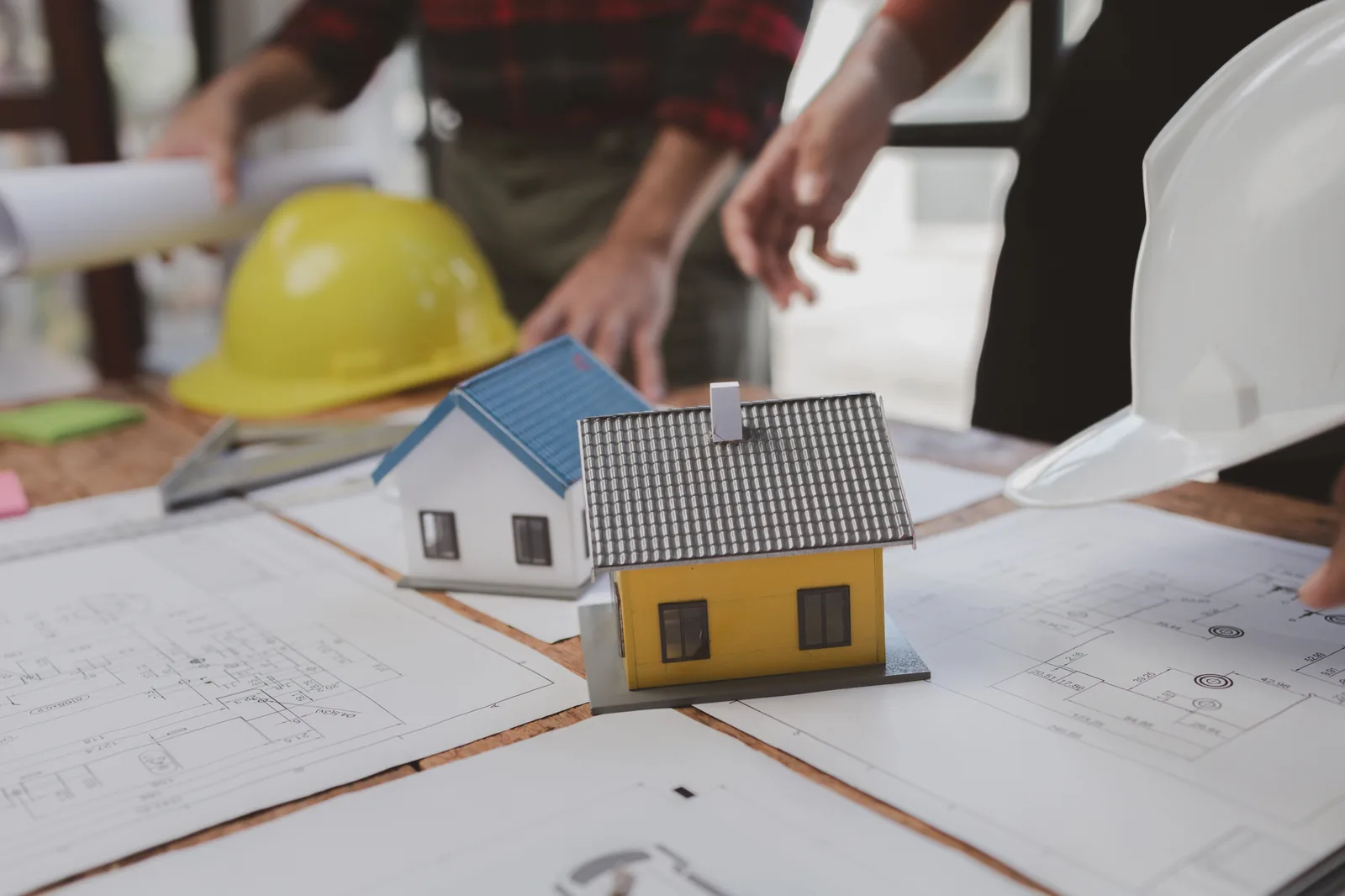 Model houses, construction plans and hard hats on a planning table