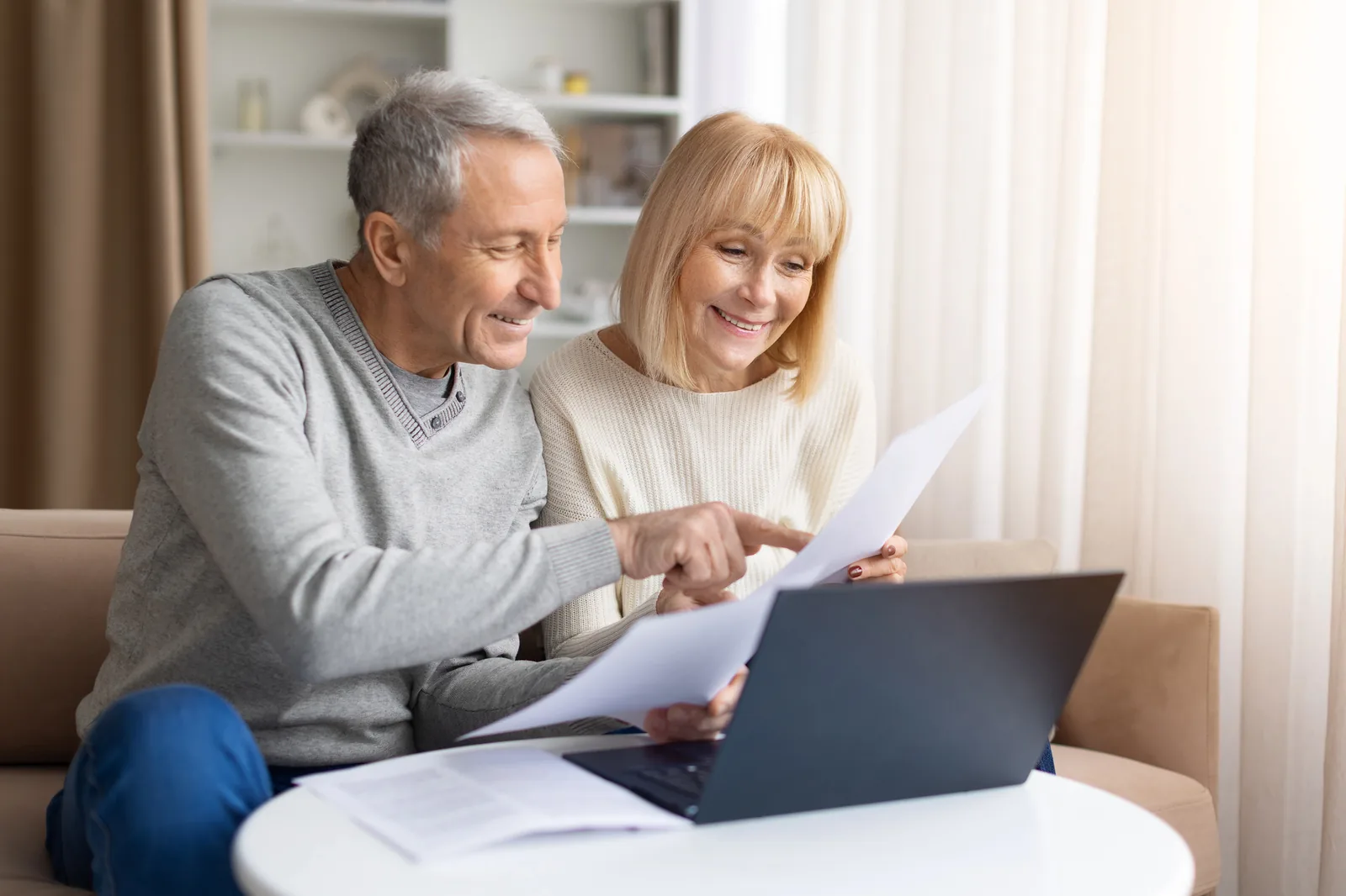 Couple reviewing paperwork together beside a laptop